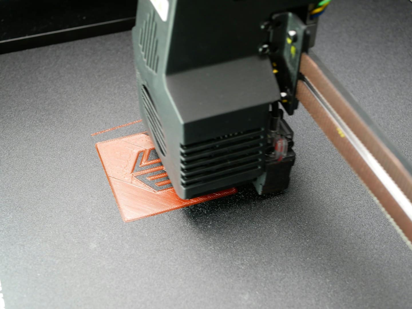 3D-skrivare som extrudera orange filament för att skapa ett litet objekt.