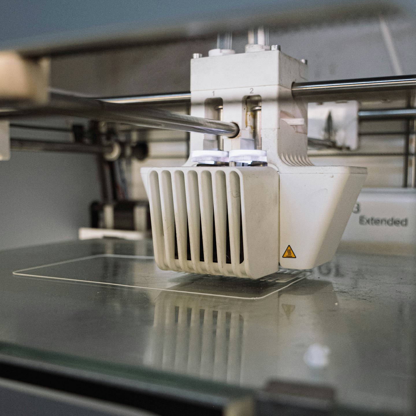 3D-skrivarhuvud som lägger ner genomskinligt filament på glas.